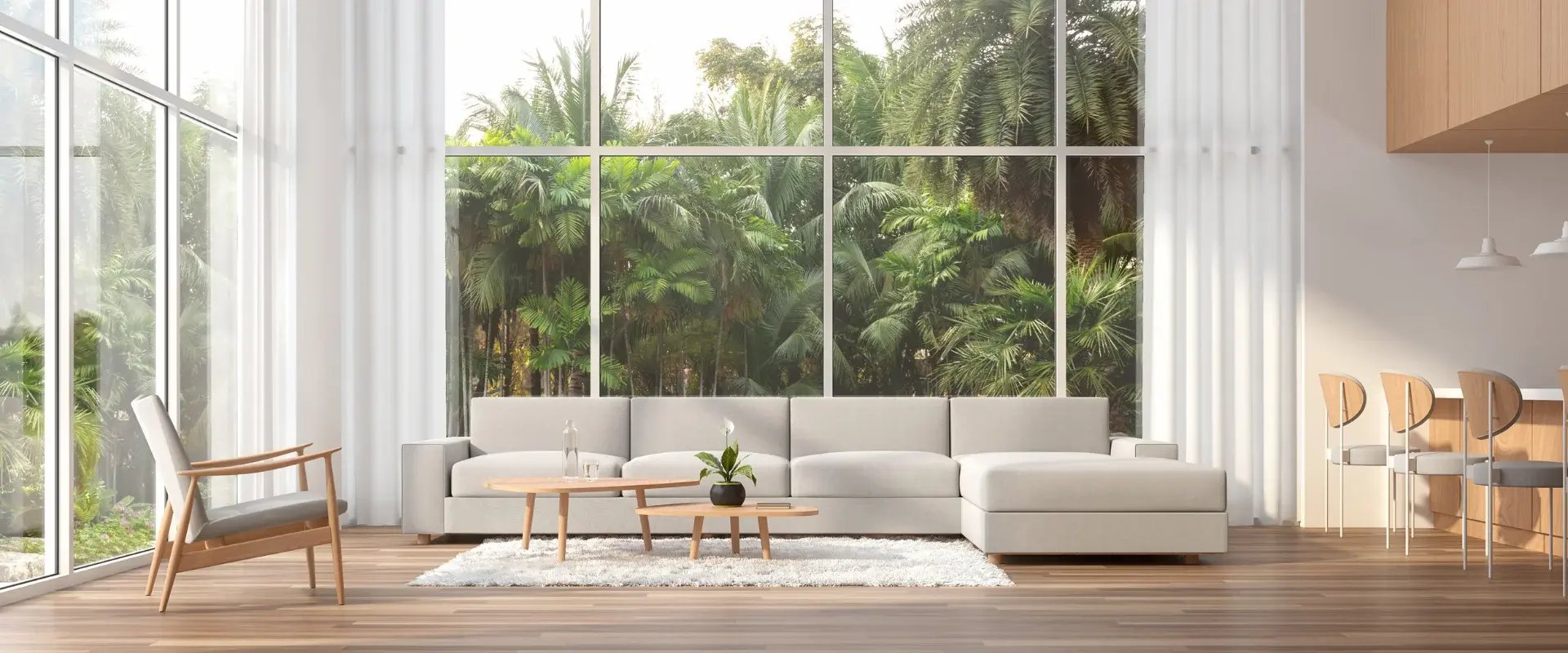 Bright, modern living room with floor-to-ceiling windows and greenery outside — representing a healthy, comfortable home environment enabled by Air Theory’s mechanical ventilation design.