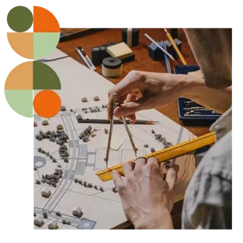 Architect using compass and ruler to design a scaled model with trees and buildings, symbolising precision and creativity. Represents Air Theory’s work with architects and building designers to deliver mechanical systems that protect design intent, meet code, run quietly and keep IAQ clean.