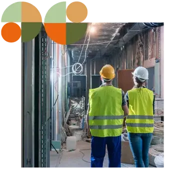 Two builders wearing safety vests and hard hats walk through a construction site with exposed wiring and framing, symbolising oversight and coordination. Represents Air Theory’s support for builders, head contractors and project managers with scope-tight, QA-driven mechanical packages.