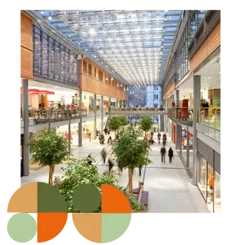 Modern shopping centre with glass roof, natural light and indoor trees, filled with people shopping and dining. Represents Air Theory’s work with commercial tenants and fit-outs to integrate mechanical services that verify comfort, calm acoustics, clean IAQ, and connect cleanly to base-build.